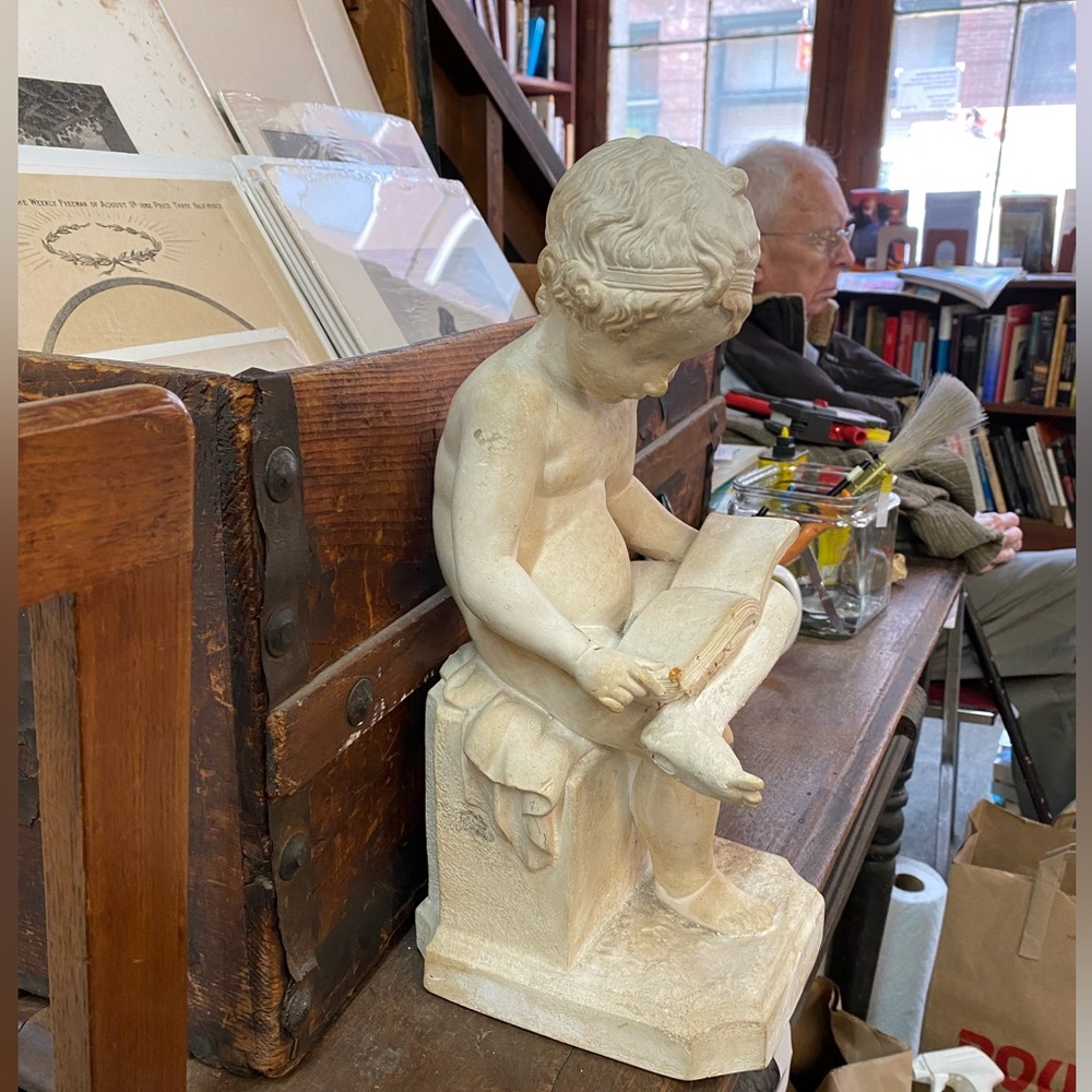 Bisque sculpture of child reading.